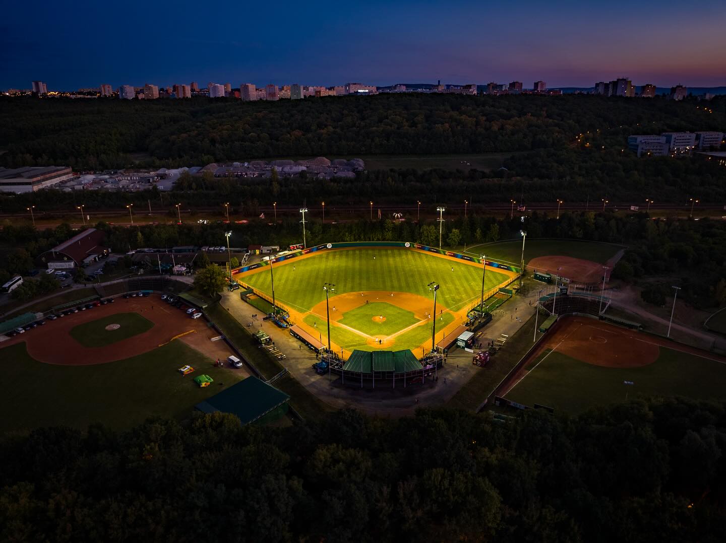 A floodlit baseball field in Prague at dusk